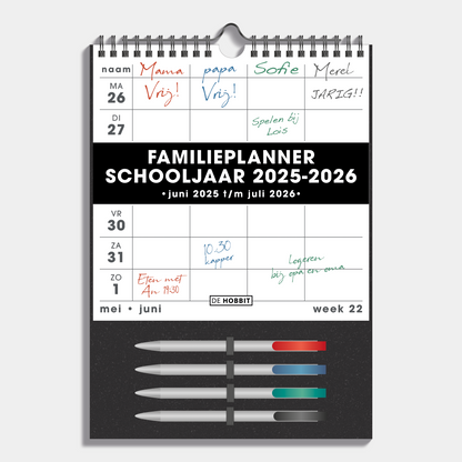 Familieplanner 2025 - 2026 A4 voor 4 personen met wit papier op een donkergrijs bord en 4 gekleurde markers – vooraanzicht.