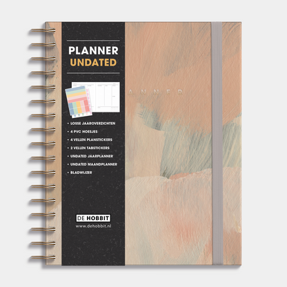 Luxe weekplanner undated A5 met een design van verfstreken in warme aardetinten, harde cover en elastische sluiting – vooraanzicht met informatieve banderol.